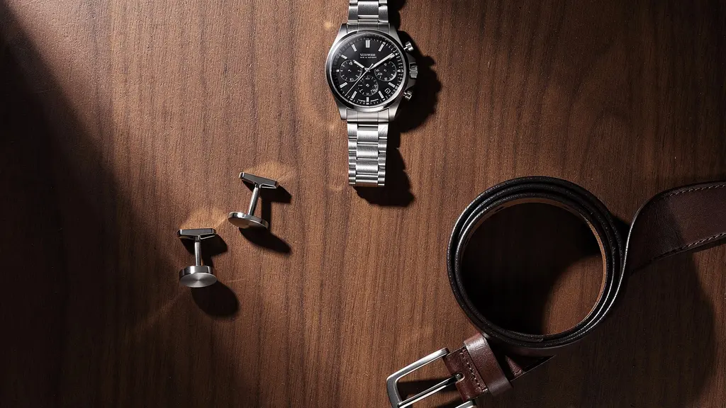 Détail d'accessoires masculins coordonnés : montre, boutons de manchette et boucle de ceinture en harmonie