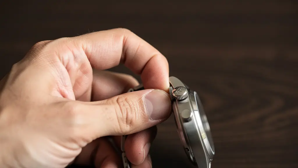 Main tenant délicatement une couronne de montre en position de remontage